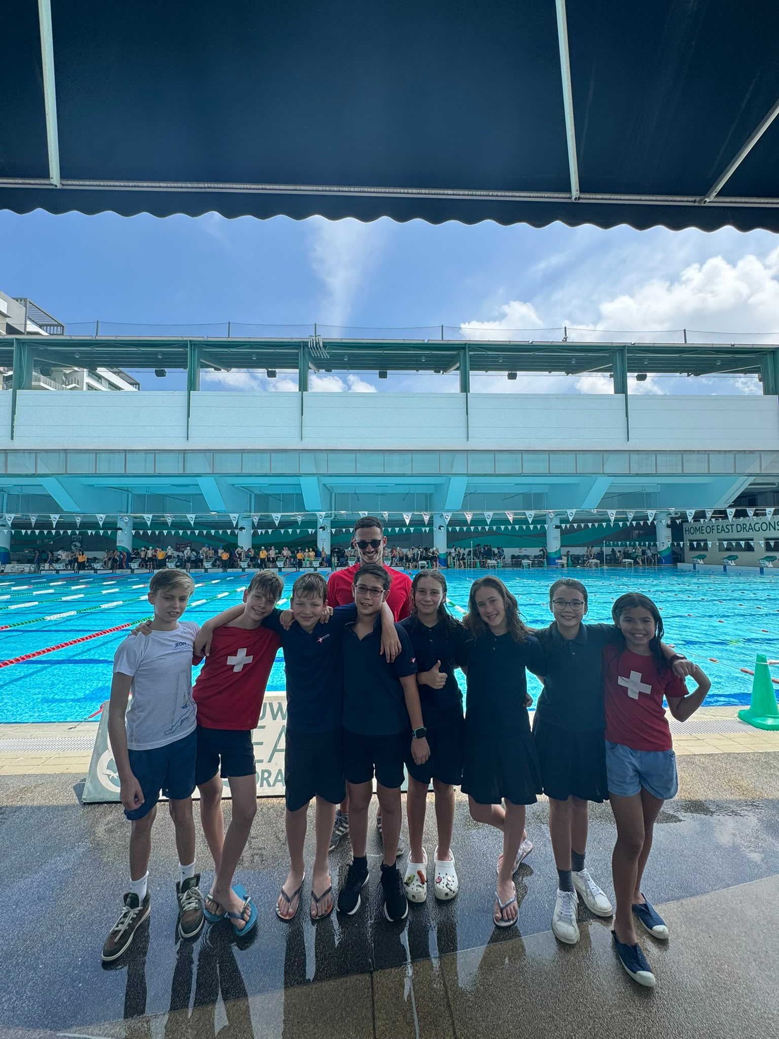 Coach Tiago Escada with young swimmers lined up on the pool deck